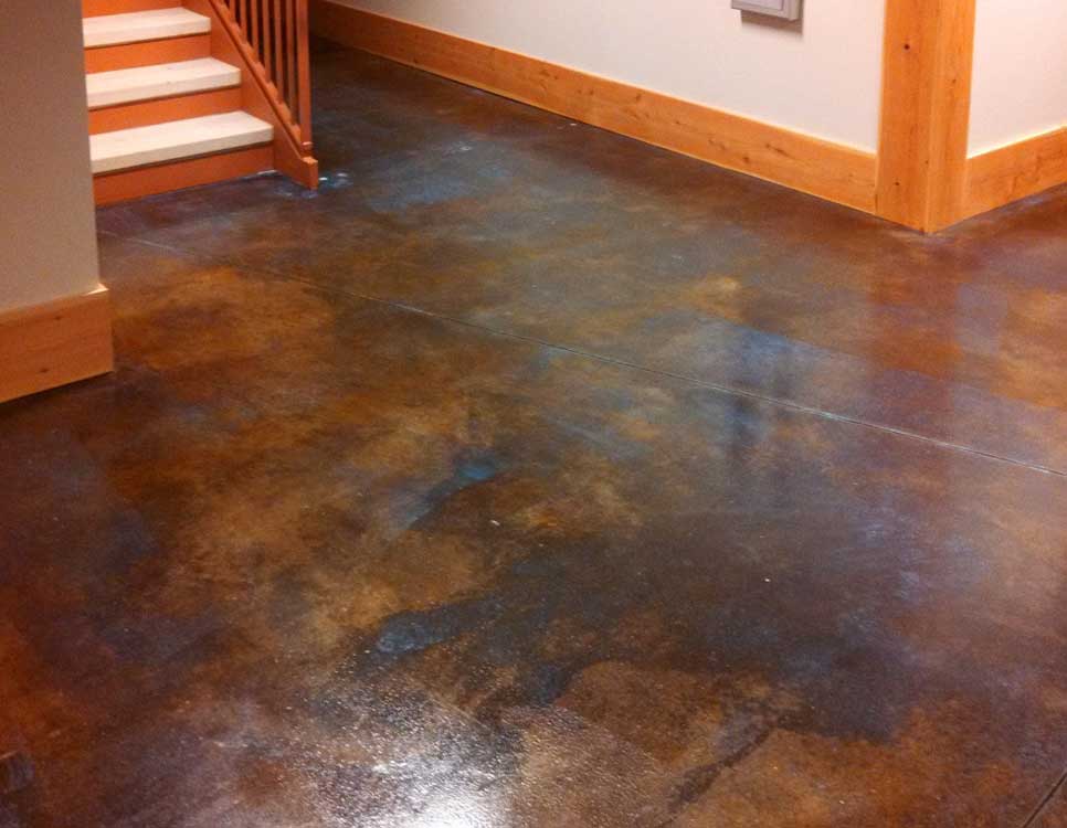 Acid Etched Metallic Flooring in a residential interior showing a rich blend of dark bronze, copper, and blue hues with a glossy, marbled finish near a staircase.