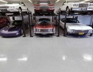 Decorative Quartz Showroom Flooring in a high-end car garage featuring a smooth, light-gray quartz finish beneath classic and luxury vehicles on lifts.