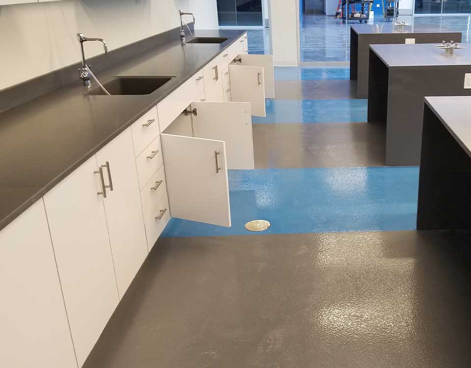 Lab Floor with Epoxy Coating featuring a two-tone gray and blue design, durable surface, and seamless finish for a clean, professional laboratory space.