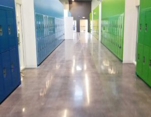 School and Educational Concrete Floor Coatings in a brightly lit hallway with polished concrete floors, blue and green lockers, and a modern design.