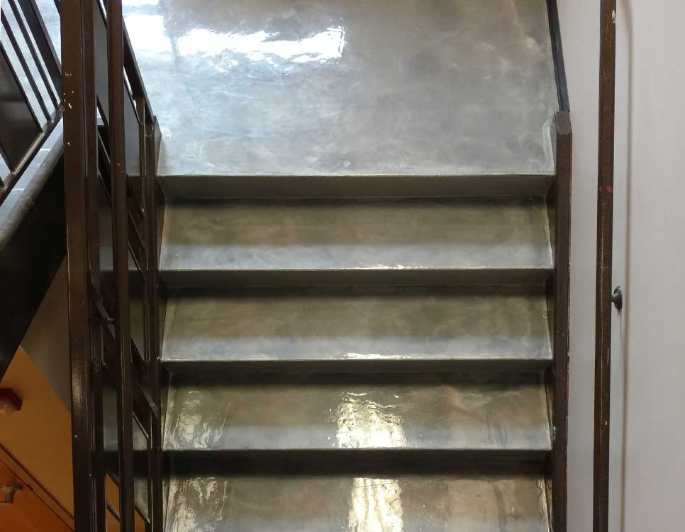 Polished Concrete Stairway Coatings applied to an indoor stairwell with a high-gloss, durable finish and metal railings for enhanced safety and style.