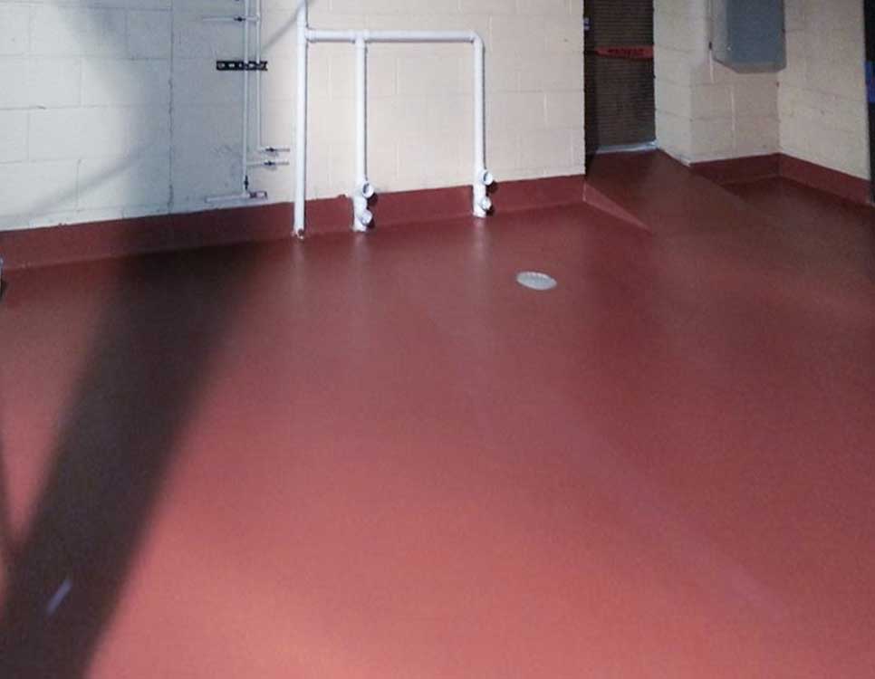 Red Cast Flooring installed in a utility room with seamless, non-slip red epoxy coating and integrated wall base for durability and chemical resistance.