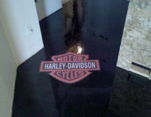 Decorative Floor Coatings Featuring Logo or Designs with a high-gloss black epoxy finish and embedded Harley-Davidson logo in a custom interior space.