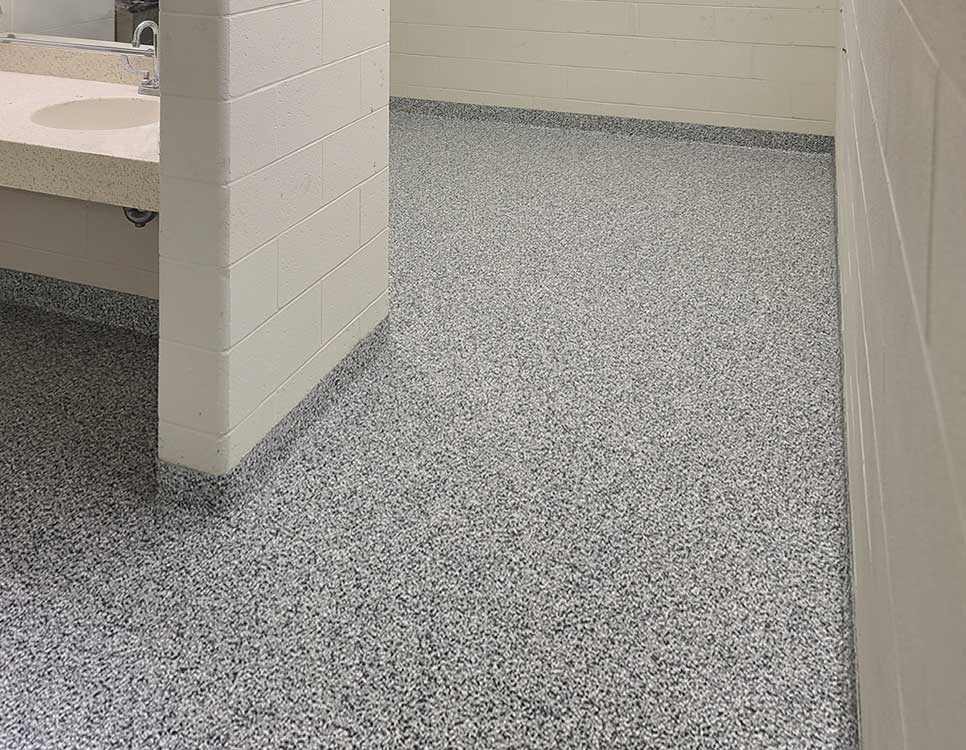 Stranlok Coating and Quartz Flooring system applied in a commercial restroom, featuring seamless quartz floor and durable wall protection for hygienic environments.