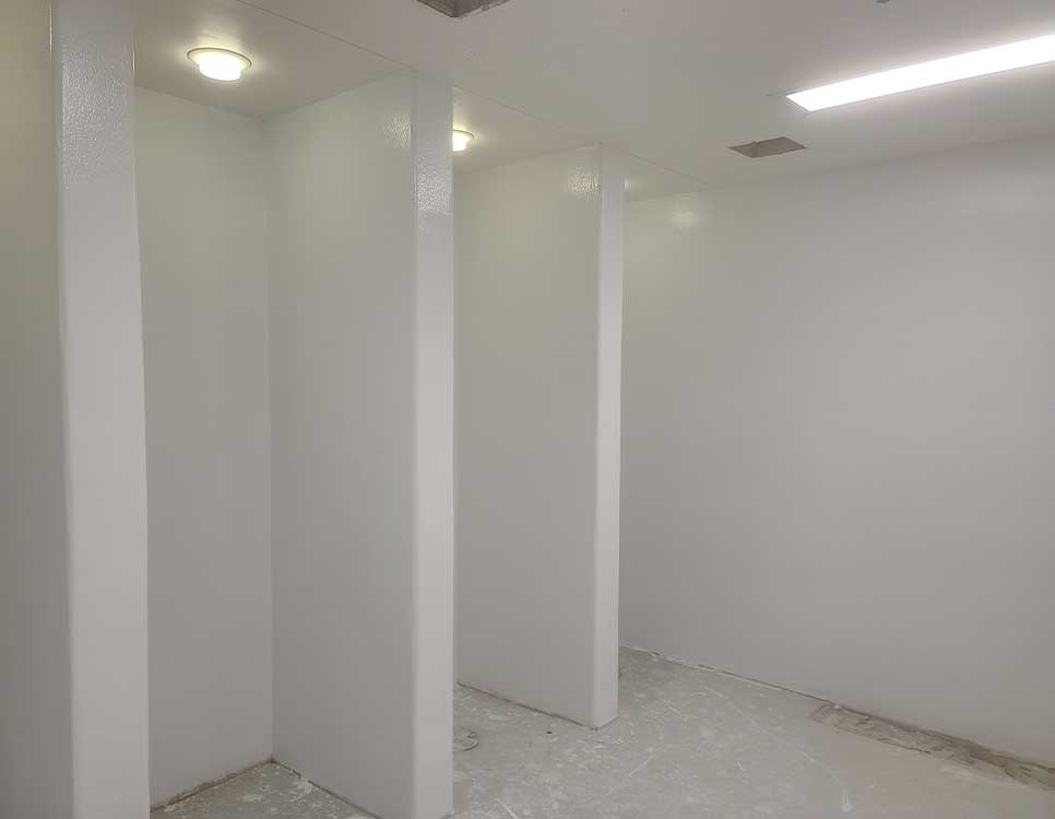 Stranlock Wall and Floor Coating Systems applied in a commercial or industrial room with smooth, seamless white walls and ceilings under bright lighting.