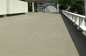 Exterior Concrete Sealants Coating applied to a large outdoor surface near a modern building entrance with geometric wall art and clean architectural lines.