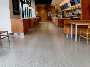 Sweet Green Polished Concrete flooring in a modern fast-casual restaurant, showcasing a sleek, reflective finish with wood and metal furnishings.