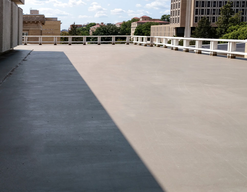 Outdoor Coatings & Sealants on a rooftop surface with a smooth, even finish, providing durable protection and surrounded by white safety railings.